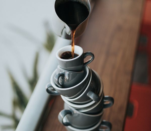 Kaffe hälls i kaffekoppar staplade på varandra.